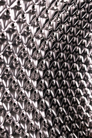 Futuristic and modernist background in polished and bright aluminum or steel with defined pattern and holes in the shape of circlesの写真素材