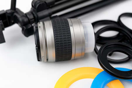 Photo camera lens close-up, with lens protectors and small tripod on white background