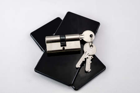 keychain with keys inserted in a lock on two black mobile phones on white background