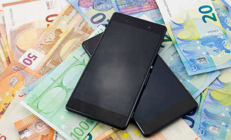 Mobile phones on a background of different euro bills