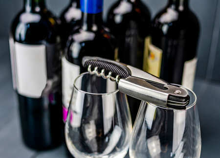 Traditional corkscrew on glass wine glasses and bottles of red wine in the background ready to be...