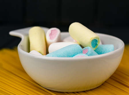 A heap of various colors candy sponges in a white bowl