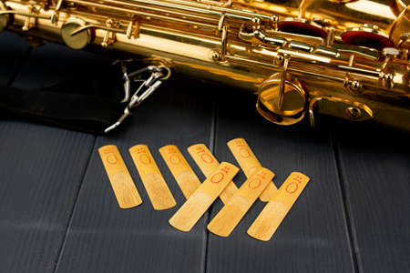 Mouthpiece reeds of a saxophone with a tenor sax on gray wooden background