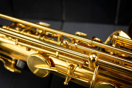 Body, rods and keys of a golden saxophone on gray wooden background