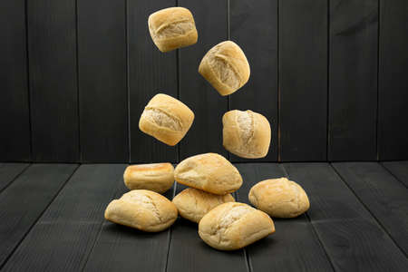 Loaf tender bread, golden and crisp, falling and stacking on a gray wooden table in a bakeryの写真素材