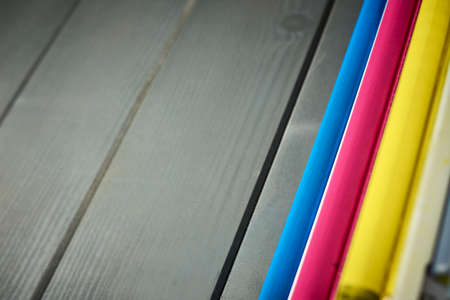 Side view of rollers in a set of laser printer color cartridges on gray wooden background