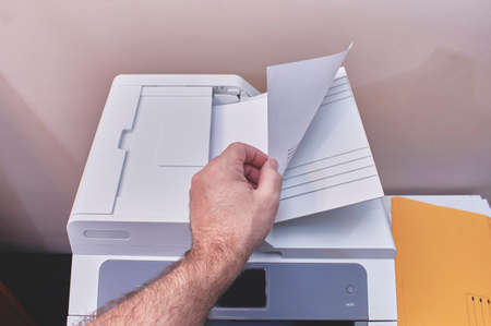 A person is making photocopies or printing documents in an officeの写真素材