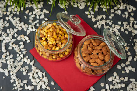 Glass jars with snacks. Unpeeled natural almonds and assorted nuts.の写真素材