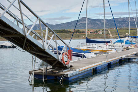 Access security walkway to the marina with boats on calm waters and mountains in the background