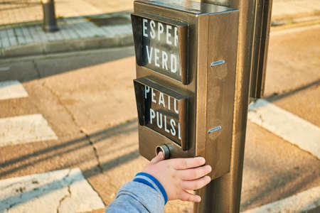 Traffic light button operated by a child who wants to cross the street safelyの写真素材