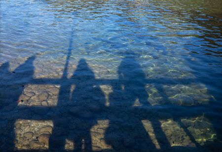 Shadows of people reflected in the clear water of the lake.の写真素材