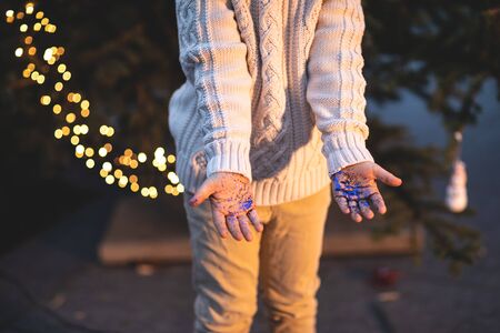 The child holds blue sparkles in his hands, vintage style, festive background, Christmas bokeh.
