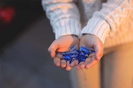 The child holds Christmas blue sparkles in his hands, vintage style, Christmas background.の写真素材
