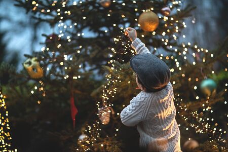 The boy decorates the Christmas tree, vintage style, festive background, Christmas bokeh.