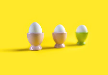 3 eggs in stands on a yellow background, only one stand in focus.の写真素材
