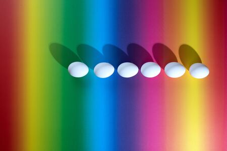 White easter eggs on a multicolored background, hard light, minimalistic concept, gradient background.の写真素材