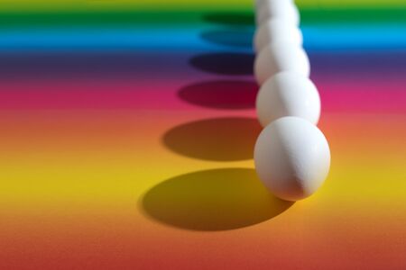 White easter eggs on a multicolored background, hard light, minimalistic concept, gradient background.の写真素材