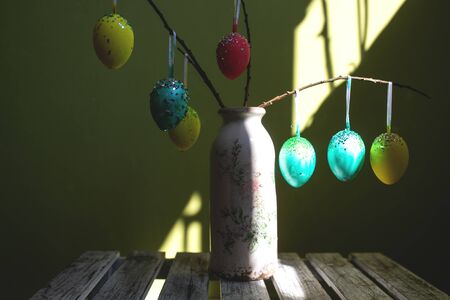 Colorful easter eggs on branches in a vase.