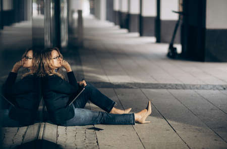 A sad business woman sits desperate on the floor with her laptop on knees.の写真素材
