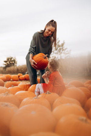 Mother and her disabled daughter spend time on a pumpkin field.