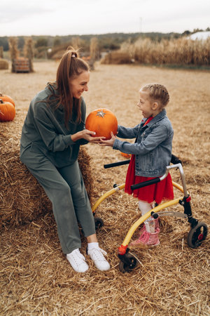 Mother and her disabled daughter spend time on a pumpkin field.の写真素材