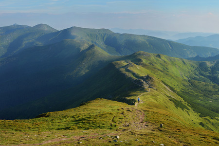Woman walking on mountain terrain on a sunny dayの写真素材