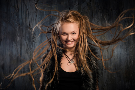 Portrait of beautiful blond woman with fluttering dreadlocks. On dark backgroundの写真素材