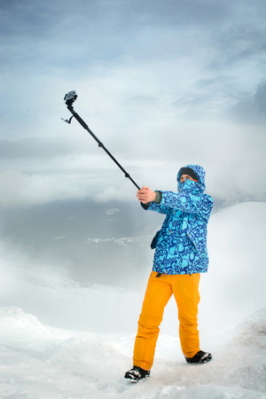 I am in the most beautiful place. Snowboarder taking selfie using action camera at the mountainsの写真素材