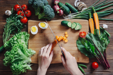 Healthy food and ingredients with tomato, salad, arugula, carrots, beet, beetroot, leaves, cucumber, onion, green, radish, mushrooms, garlic, broccoli, half, egg and peas on rustic wooden background, top viewの写真素材