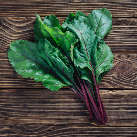 Close up of fresh beetroot leaves on rustic wooden background, top viewの写真素材