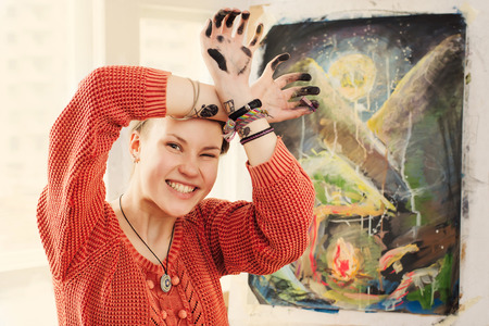 Portrait of beautiful woman artist with quirky expressions and touching her face in home art studioの写真素材