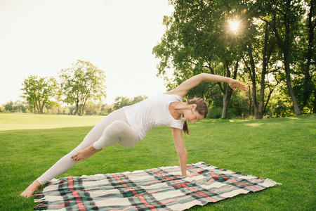 Woman doing gymnastics and stretching on the nature on sunsetの写真素材