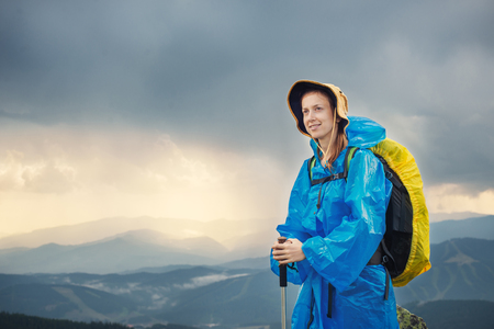 Women hiking with trekking sticks and backpack holding trekking sticks in rainy weatherの写真素材