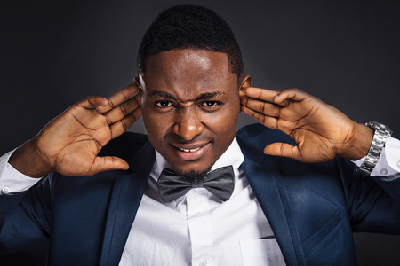 Young african american in suit man close his ears with hands and does not want to hear anythingの写真素材