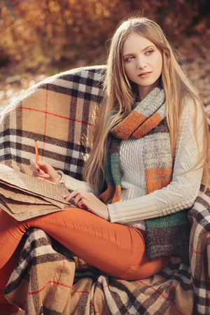 Portrait of beautiful blond woman in autumn season. Writer woman in the autumn parkの写真素材