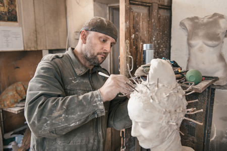 Craftsman creating shape of sculpture in his workshopの写真素材