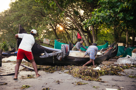 Kochi, India - November 29, 2015: Indian fishermen after fishing in their wooden boats in the early morning on the sea beach in Fort Kochi Cochin, Kerala, India.のeditorial素材