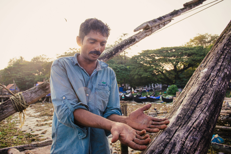 Kochi, India - November 29, 2015: Traditional technology of fishing. Fisherman shows damaged hands after hardly working on Chinese fishing net on the sea beach in Fort Kochi Cochin, Kerala, India.のeditorial素材