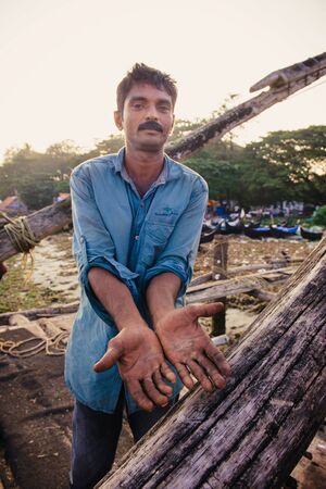 Kochi, India - November 29, 2015: Traditional technology of fishing. Fisherman shows damaged hands after hardly working on Chinese fishing net on the sea beach in Fort Kochi Cochin, Kerala, India.のeditorial素材