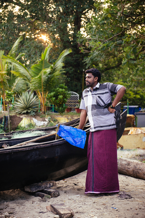 Kochi, India - November 29, 2015: Portrait of indian fisherman standing near boat on the sea beach in Fort Kochi Cochin, Kerala, India.のeditorial素材
