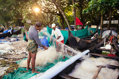 Kochi, India - November 29, 2015: Indian fishermen after fishing in their wooden boats in the early morning on the sea beach in Fort Kochi Cochin, Kerala, India.のeditorial素材