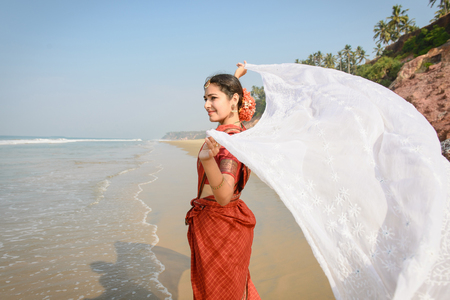 Indian woman feel freedom and standing near the beach in traditional saree clothing with white tissue in the handsの写真素材