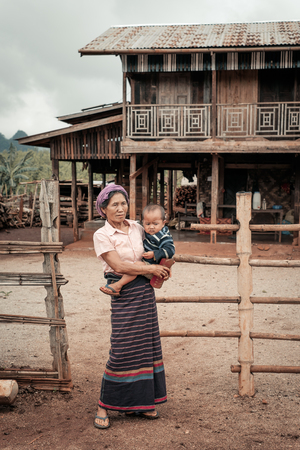 Loikaw, Myanmar - May 25, 2016: Woman from remote village in Myanmar standing with child near the traditional houseのeditorial素材