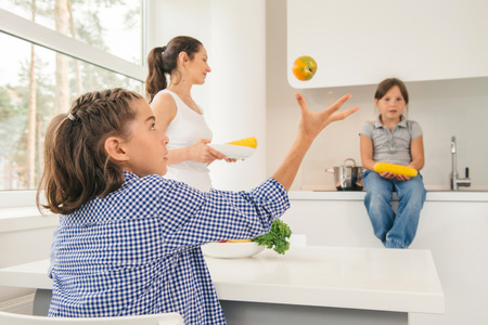 Young mother and daughters eating healthy food in kitchen. Concept healthy lifestyle in modern familyの写真素材