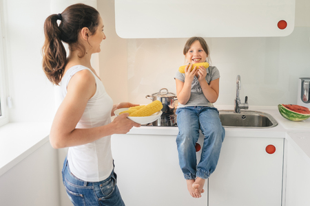 Young mother preparing tasty corn for her daughter. Concept healthy lifestyle in modern familyの写真素材