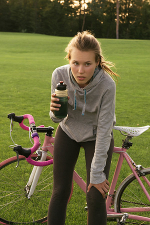 Sport woman drinking water after riding a bicycle in the park. Active lifestyleの写真素材