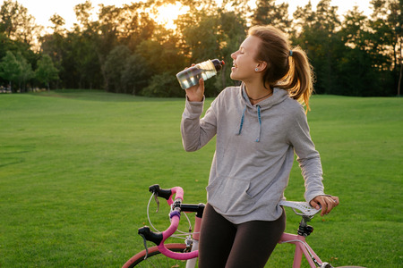 Sport woman drinking water after riding a bicycle in the park. Active lifestyleの写真素材
