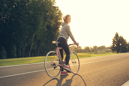 Active  young woman on bike standing on road and looking to somewhereの写真素材