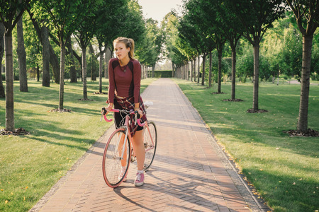 Young sport woman standing with bicycle on the road. Active lifestyle conceptの写真素材