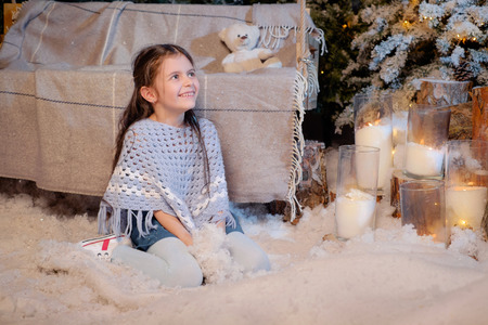 Beautiful smiling little girl playing near the christmas tree. Room decorated for New Year. Holiday atmosphere.の写真素材